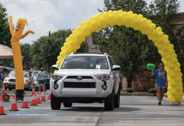 car driving through yellow ballon arch